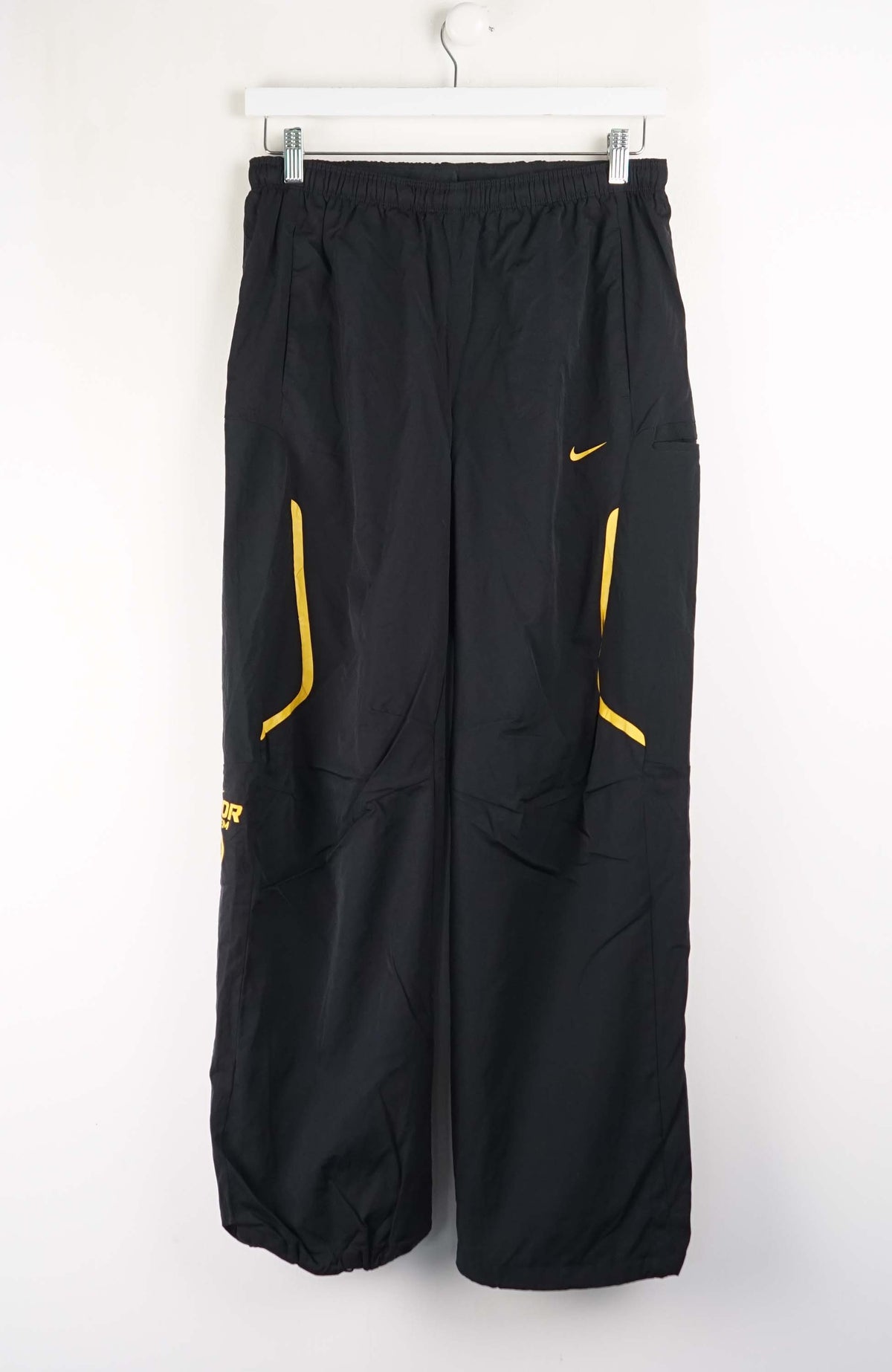 Black pants with yellow accents on a white hanger