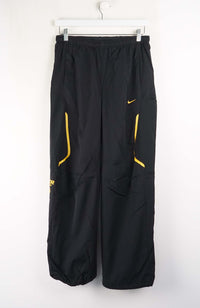 Black pants with yellow accents on a white hanger