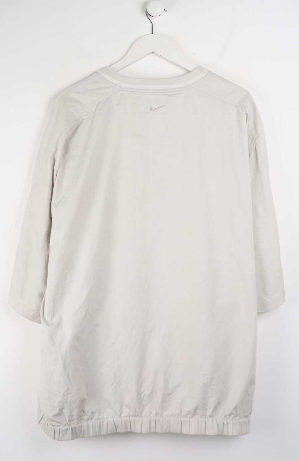 Beige V-neck shirt with a small logo on a white background