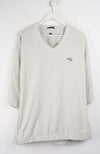Beige V-neck shirt with a small logo on a white background