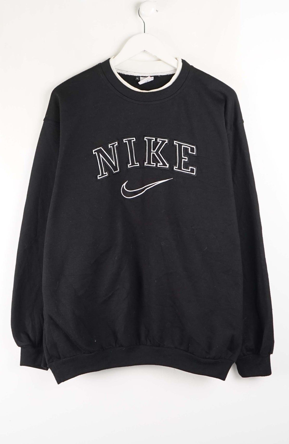 Black Nike sweatshirt on a white hanger against a white background