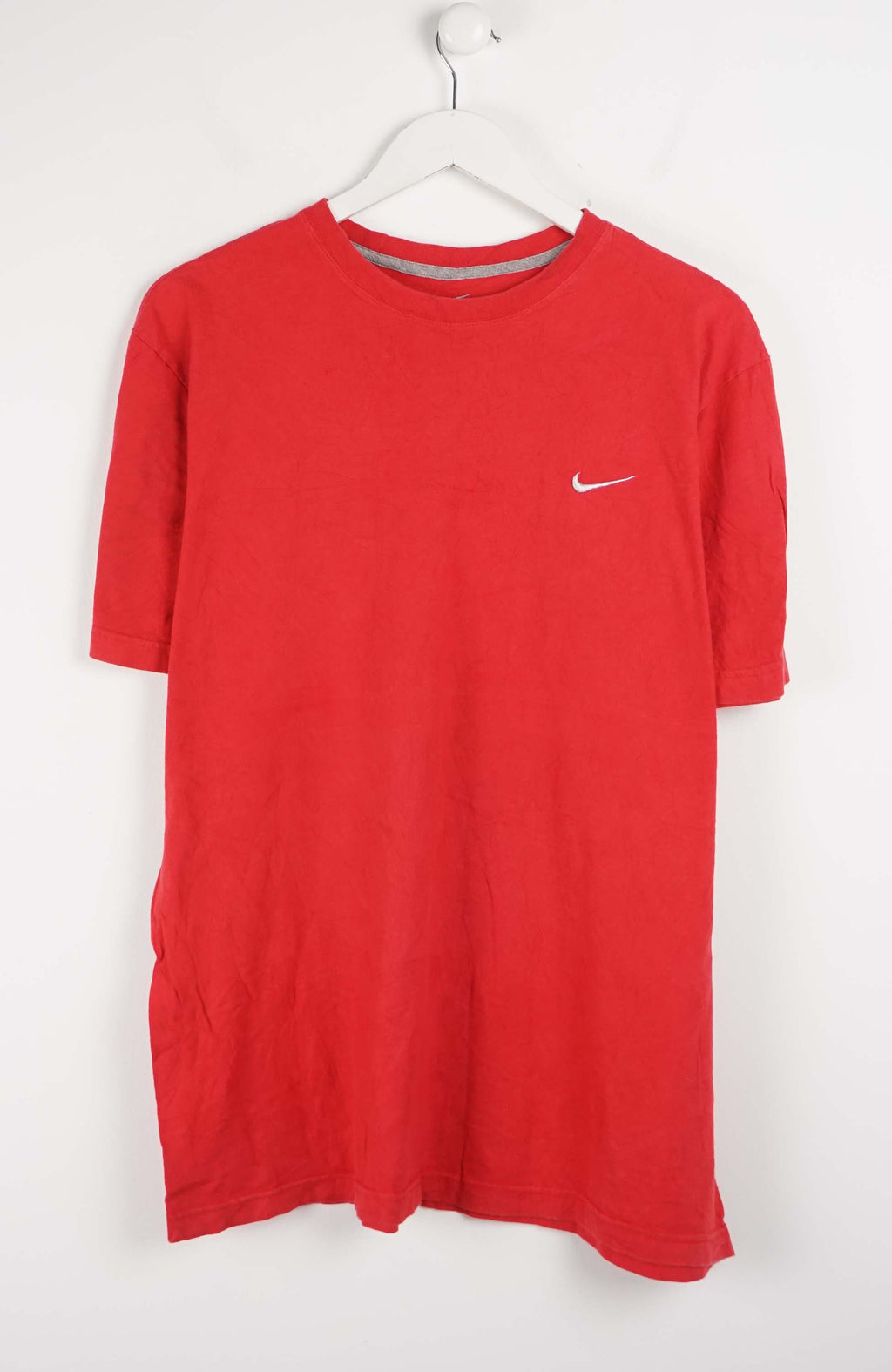 Red t-shirt with Nike logo on a white hanger against a white background