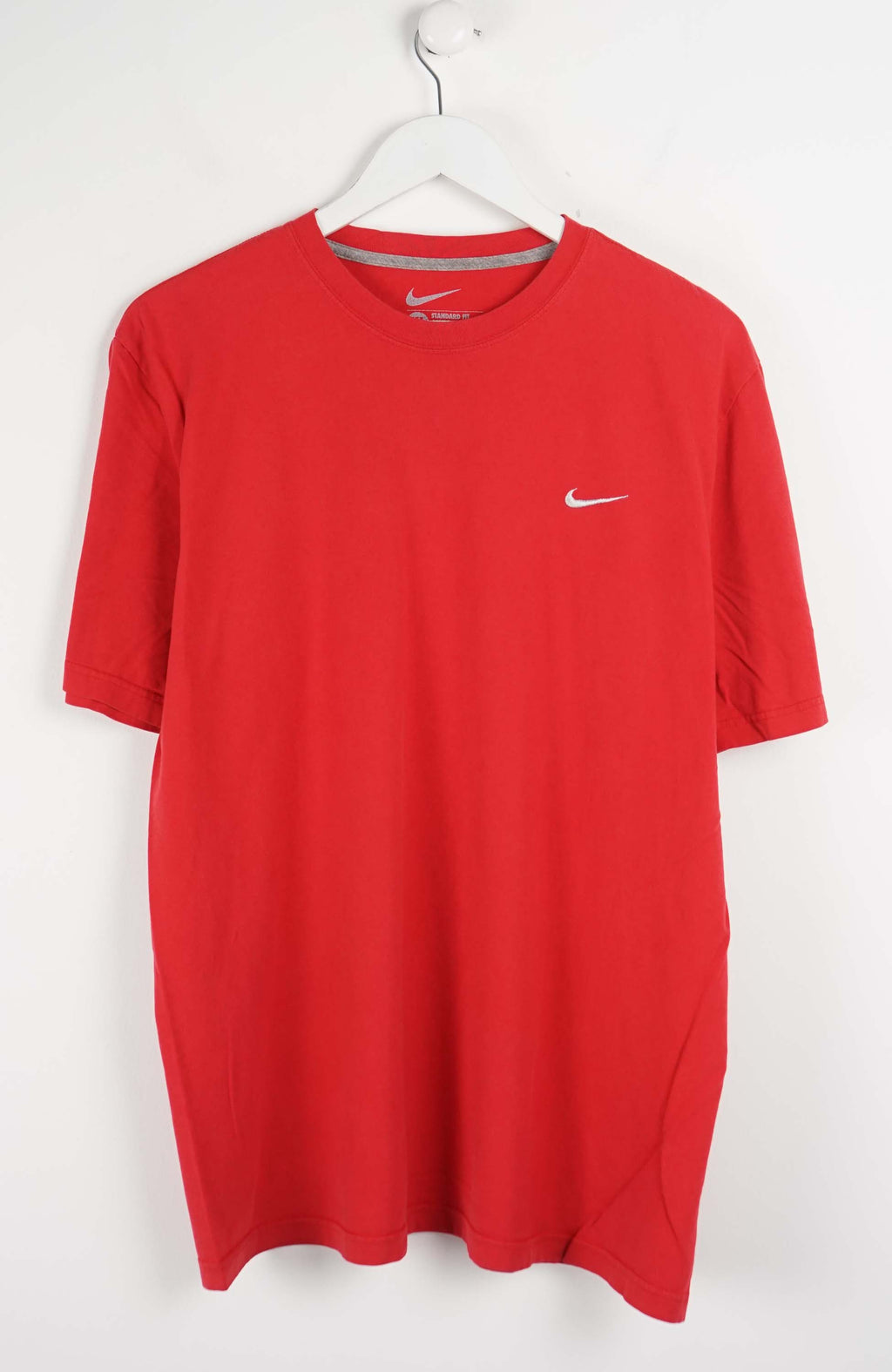 Red t-shirt with Nike logo on a white hanger against a white background
