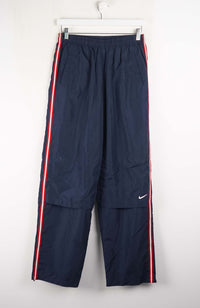 Navy blue tracksuit pants with red and white stripes on a white background