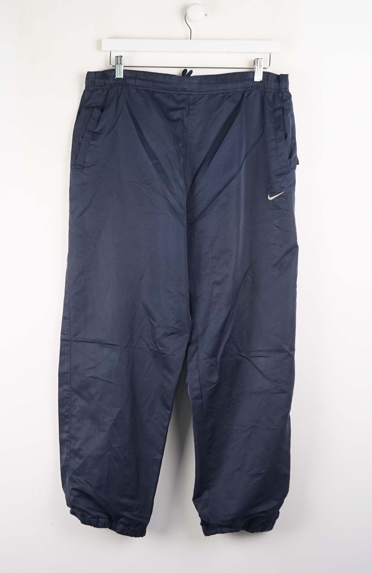 Navy blue pants with a Nike logo on a white hanger