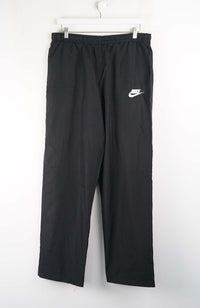 Black Nike pants hanging on a white background