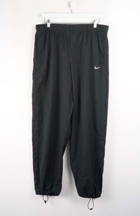 Black pants with a Nike logo on a white background