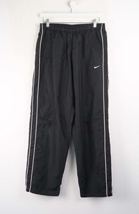 Black track pants with white stripes and Nike logo on a white background