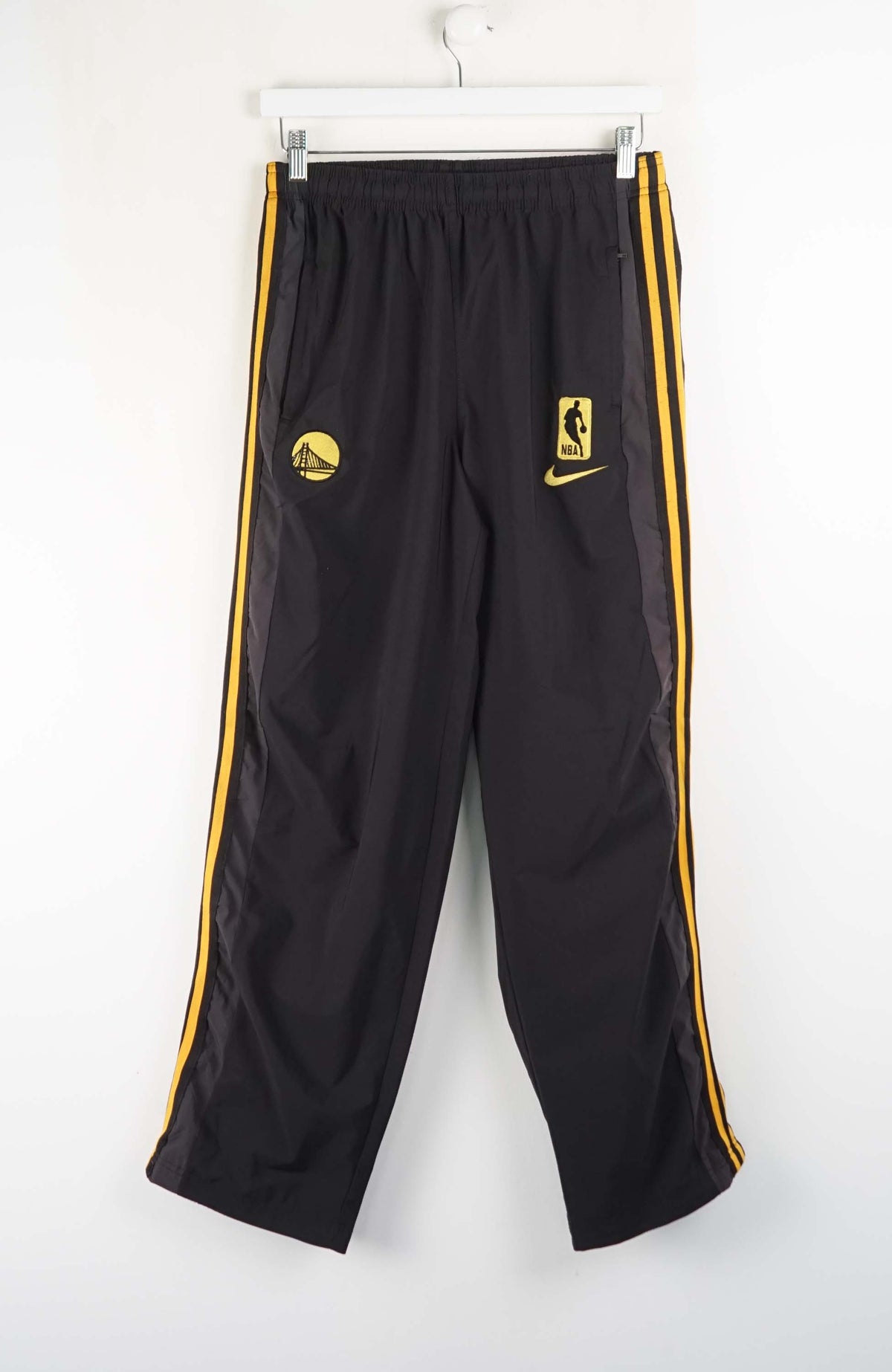Black athletic pants with yellow stripes and logos on a white background