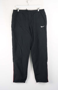Black Nike pants hanging on a white hanger against a white background
