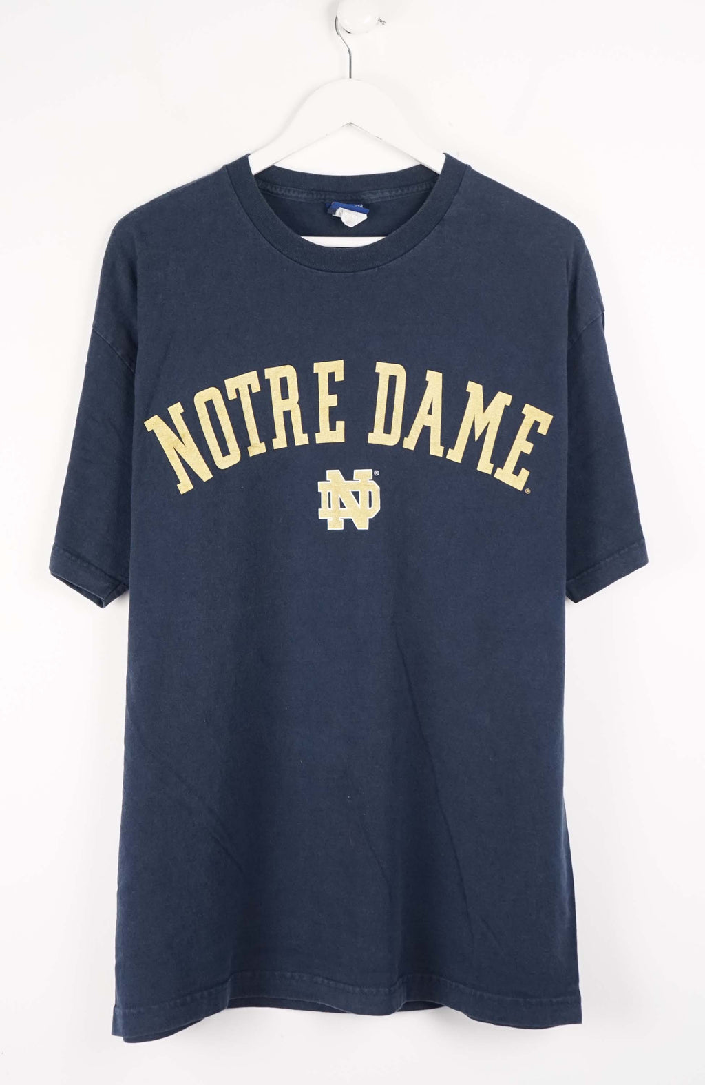 Navy blue t-shirt with 'Notre Dame' printed on it, hanging on a white hanger against a white background.