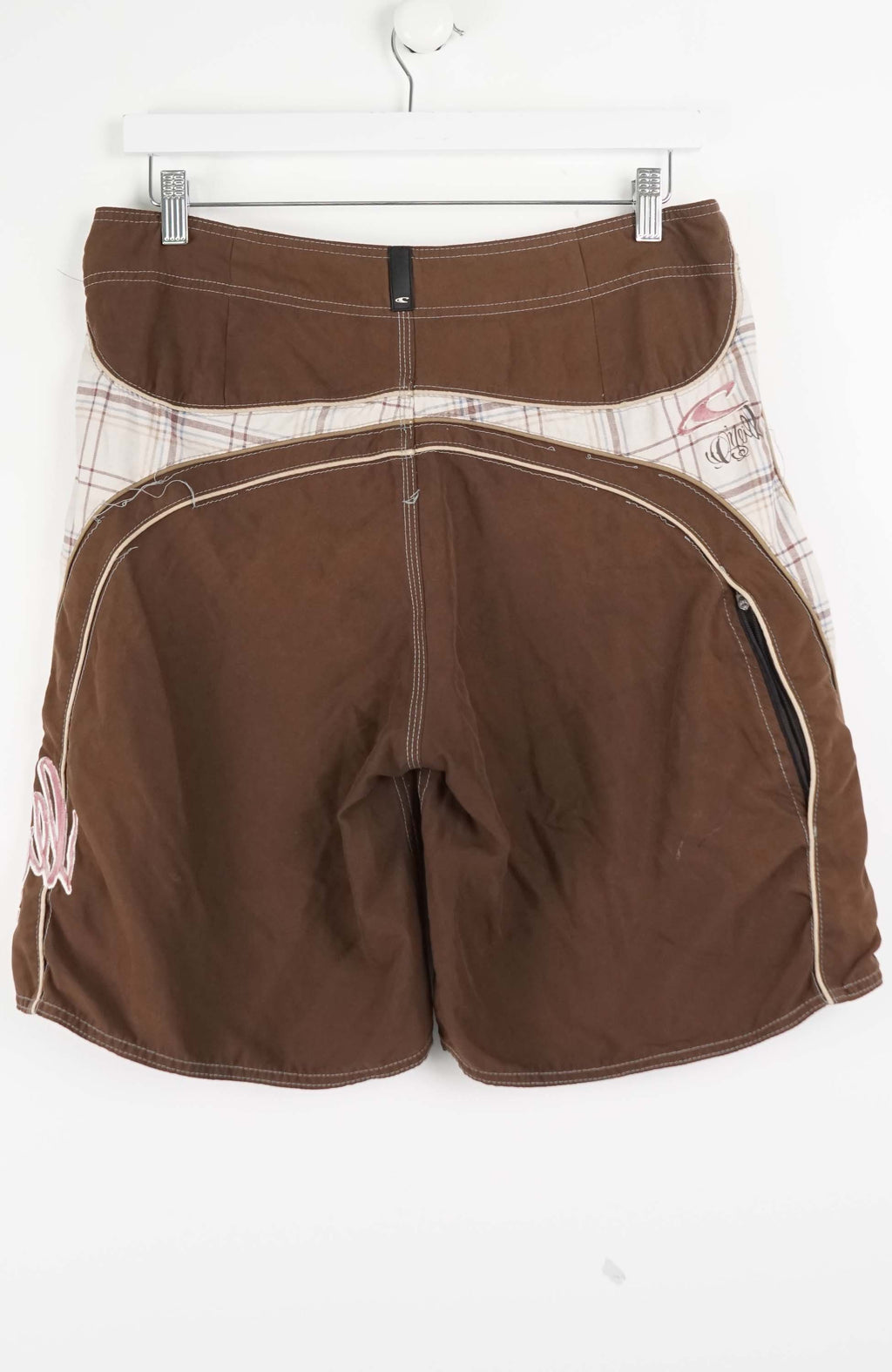 Brown shorts on a hanger against a white background