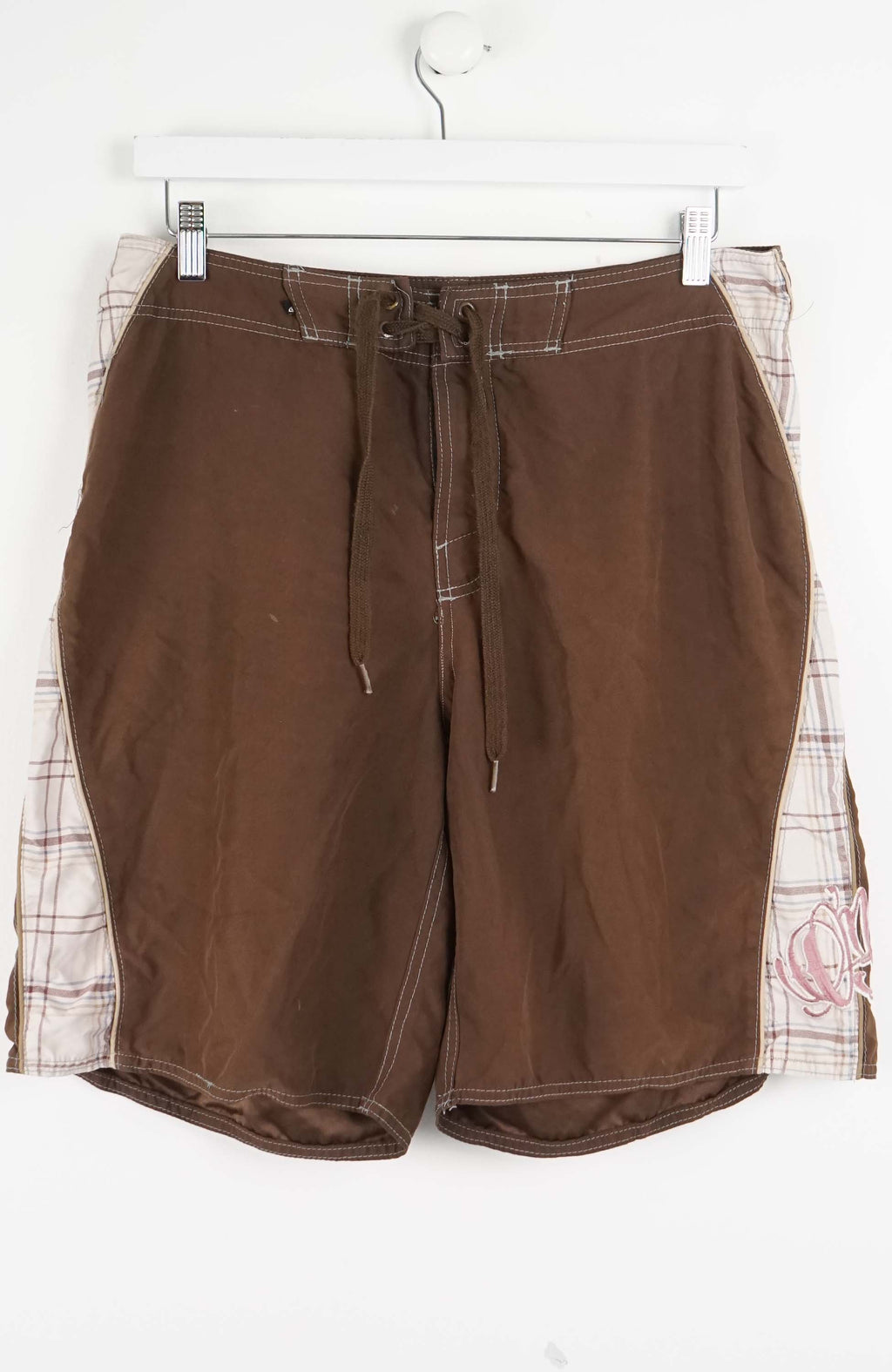 Brown shorts on a hanger against a white background