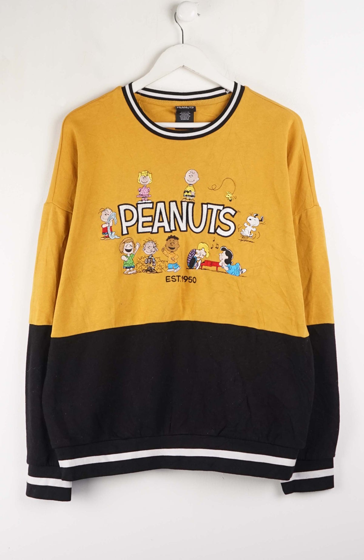 Yellow and black sweatshirt with Peanuts character design on a white background
