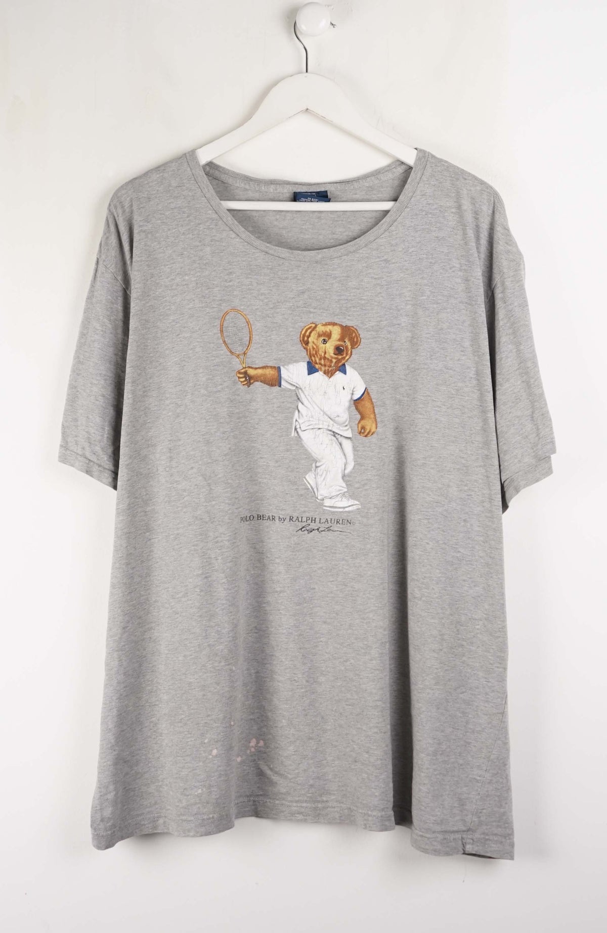 Gray t-shirt with a bear graphic holding a tennis racket on a white background