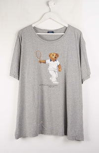 Gray t-shirt with a bear graphic holding a tennis racket on a white background