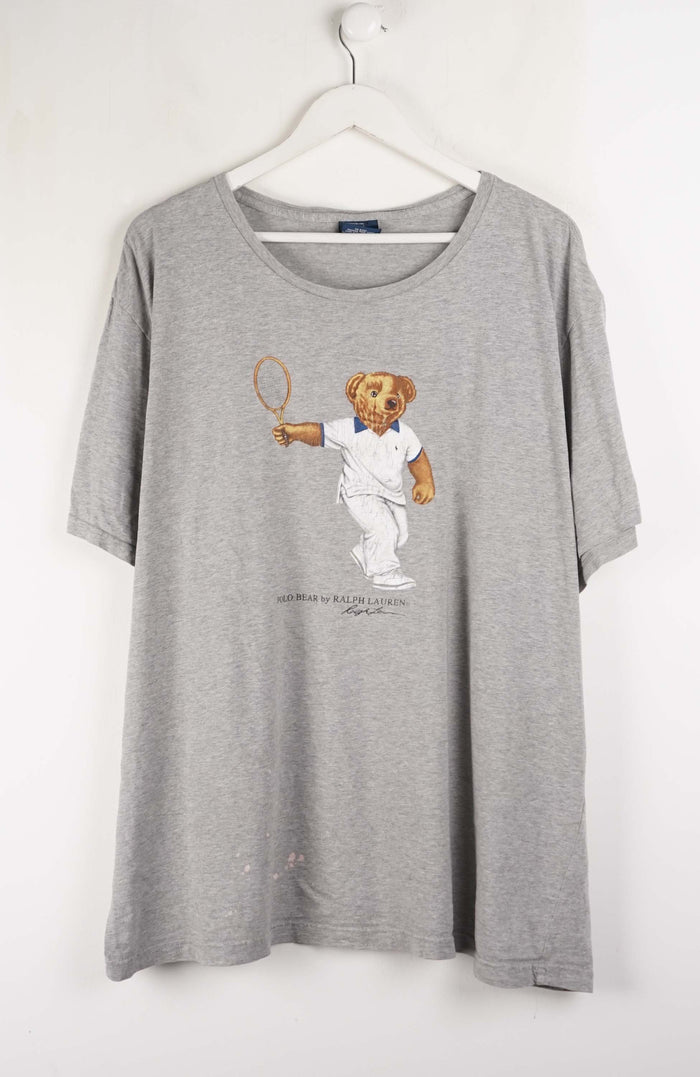 Gray t-shirt with a bear graphic holding a tennis racket on a white background