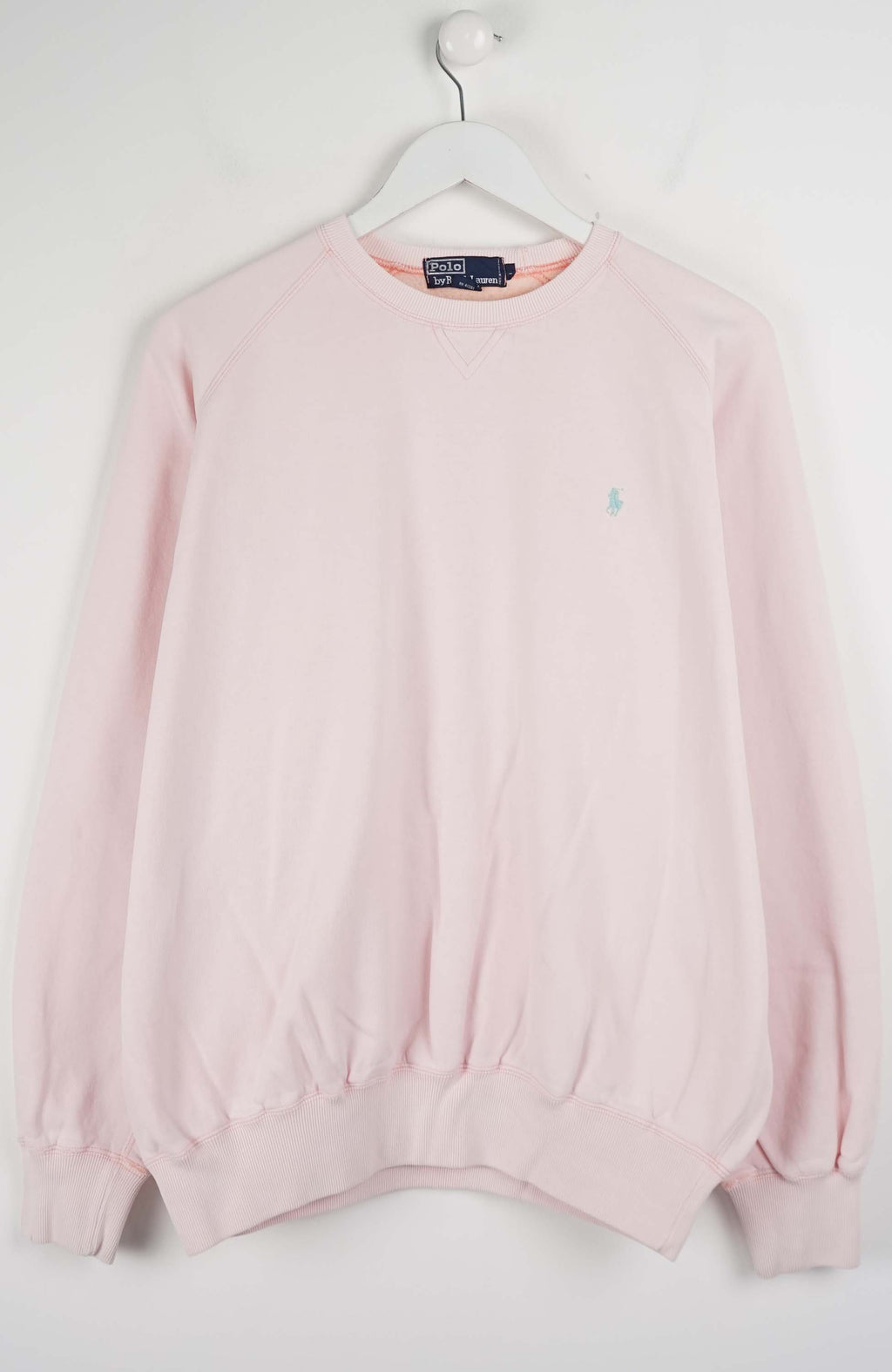 Pink sweater on a hanger against a white background
