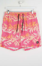 Pink swim shorts with tropical leaf pattern on a white background