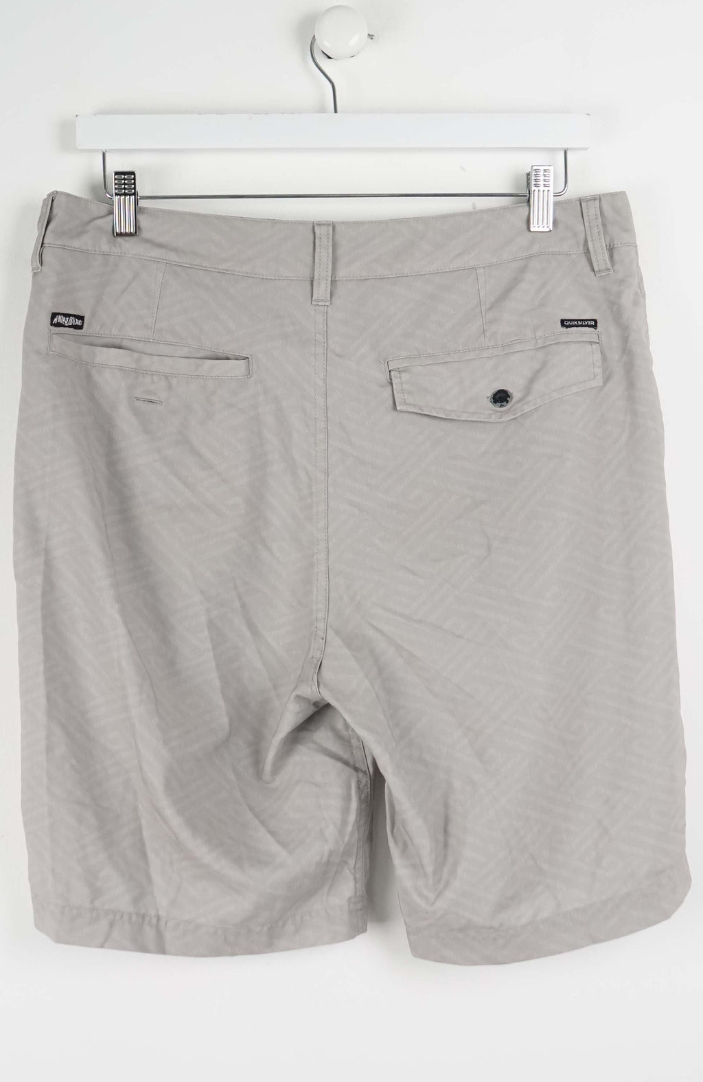 Gray shorts hanging on a white hanger against a white background