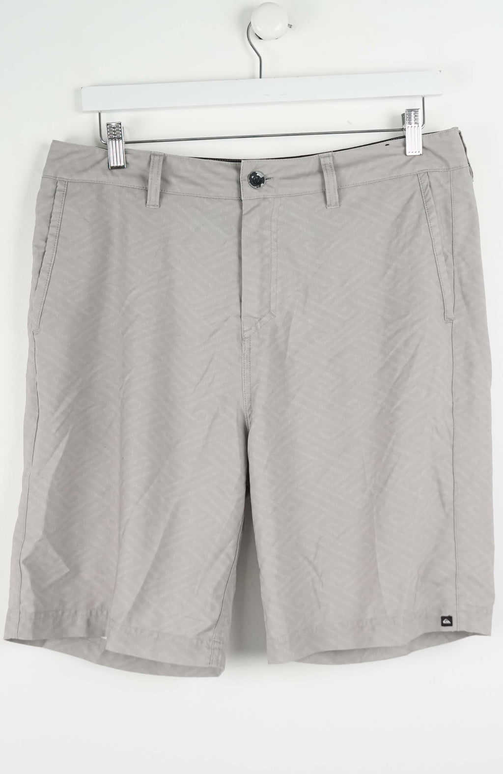 Gray shorts hanging on a white hanger against a white background