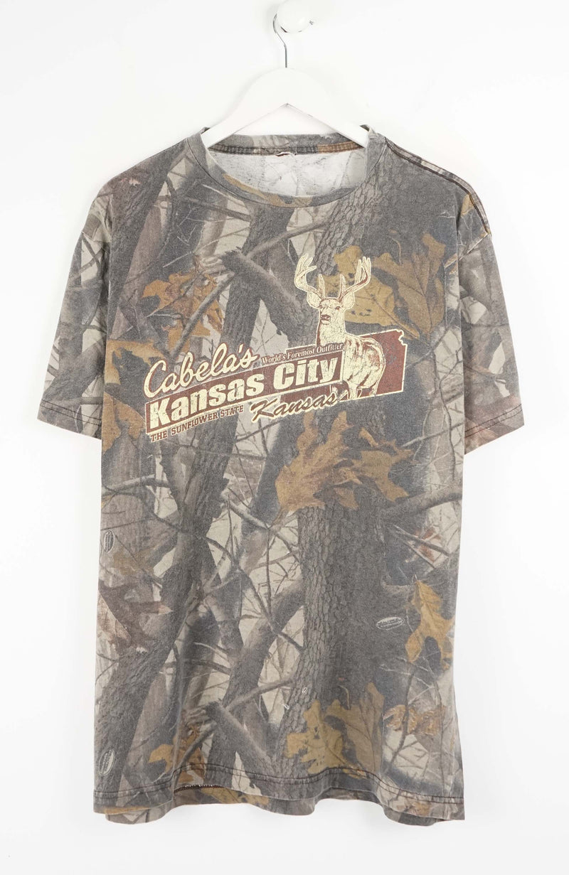Camouflage-patterned t-shirt with Cabela's branding on a white background