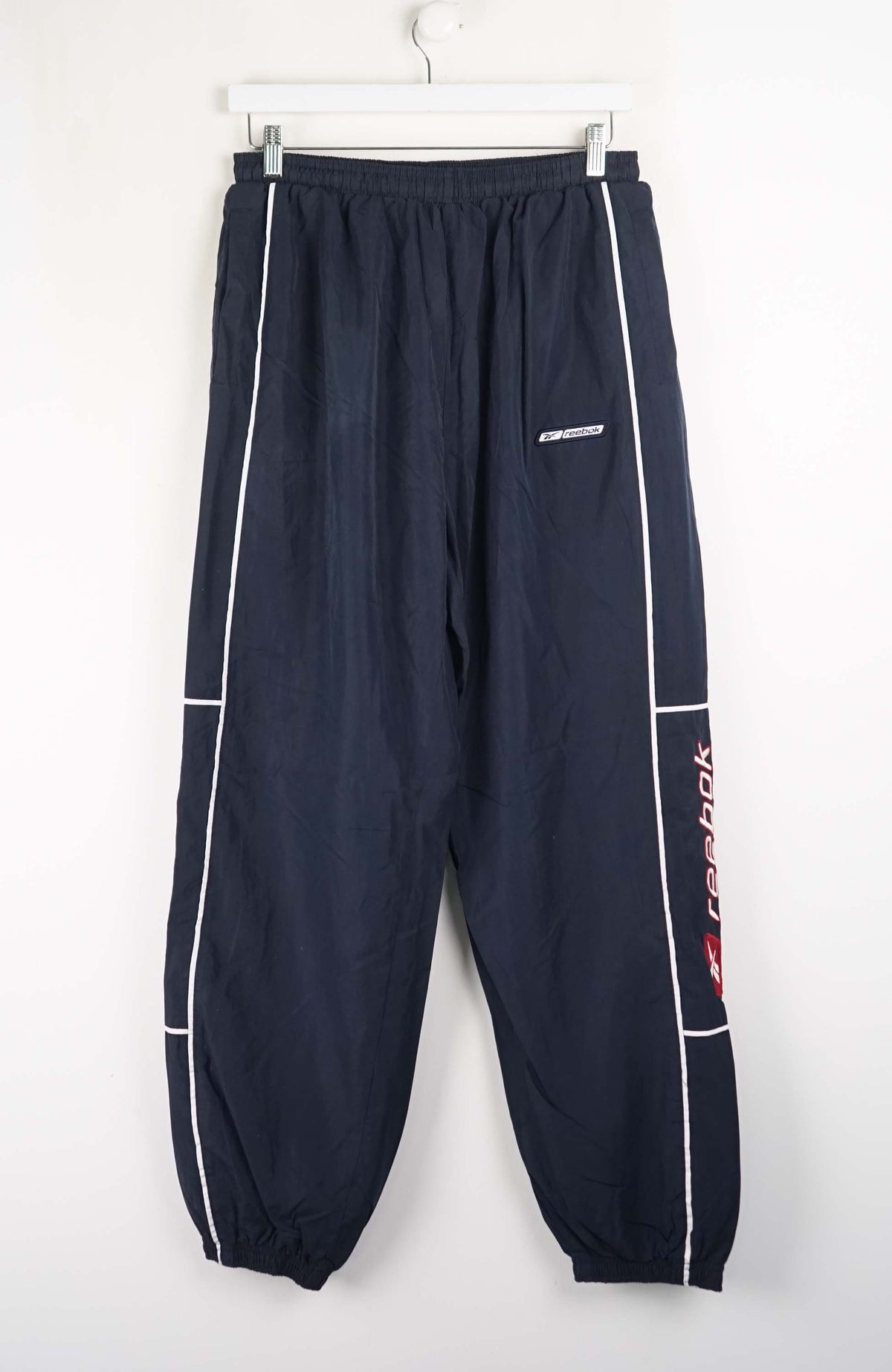Navy blue pants with white and red accents on a white background