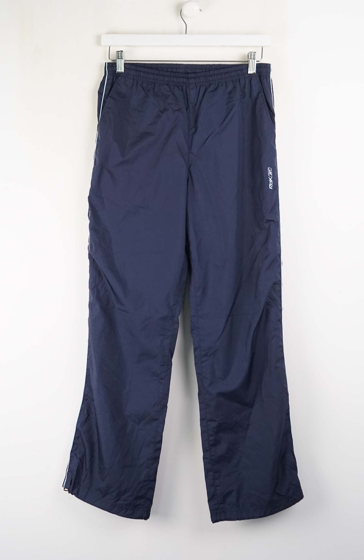 Navy blue pants hanging on a white hanger against a white background