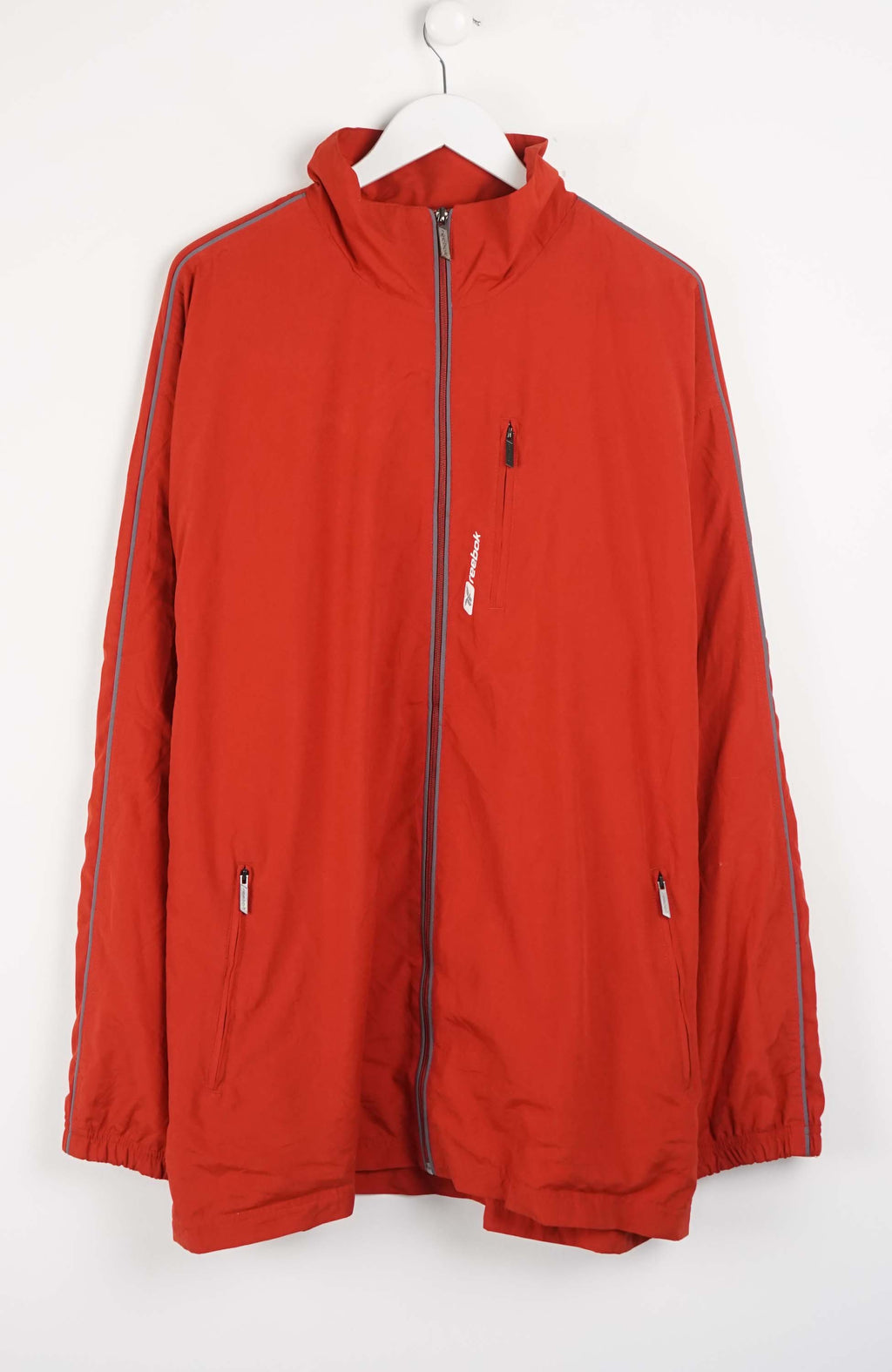 Red jacket with white stripes on sleeves hanging on a white background