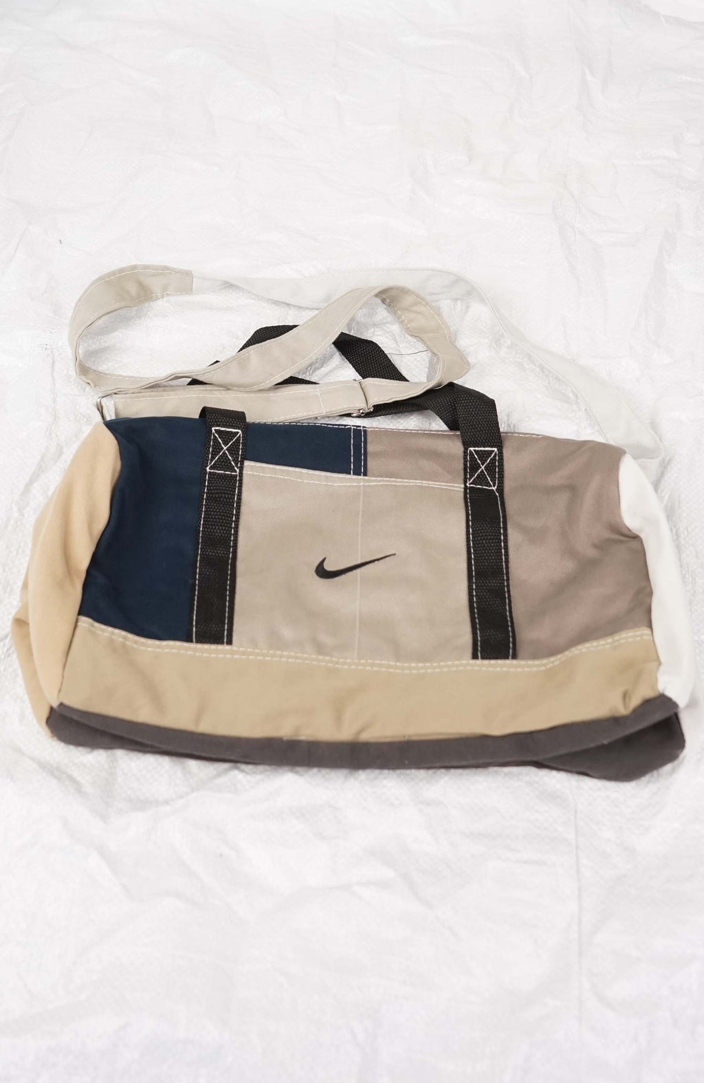 Beige and navy duffel bag with Nike logo on a white background