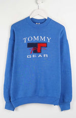 Blue Tommy Gear sweatshirt on a white hanger against a white background