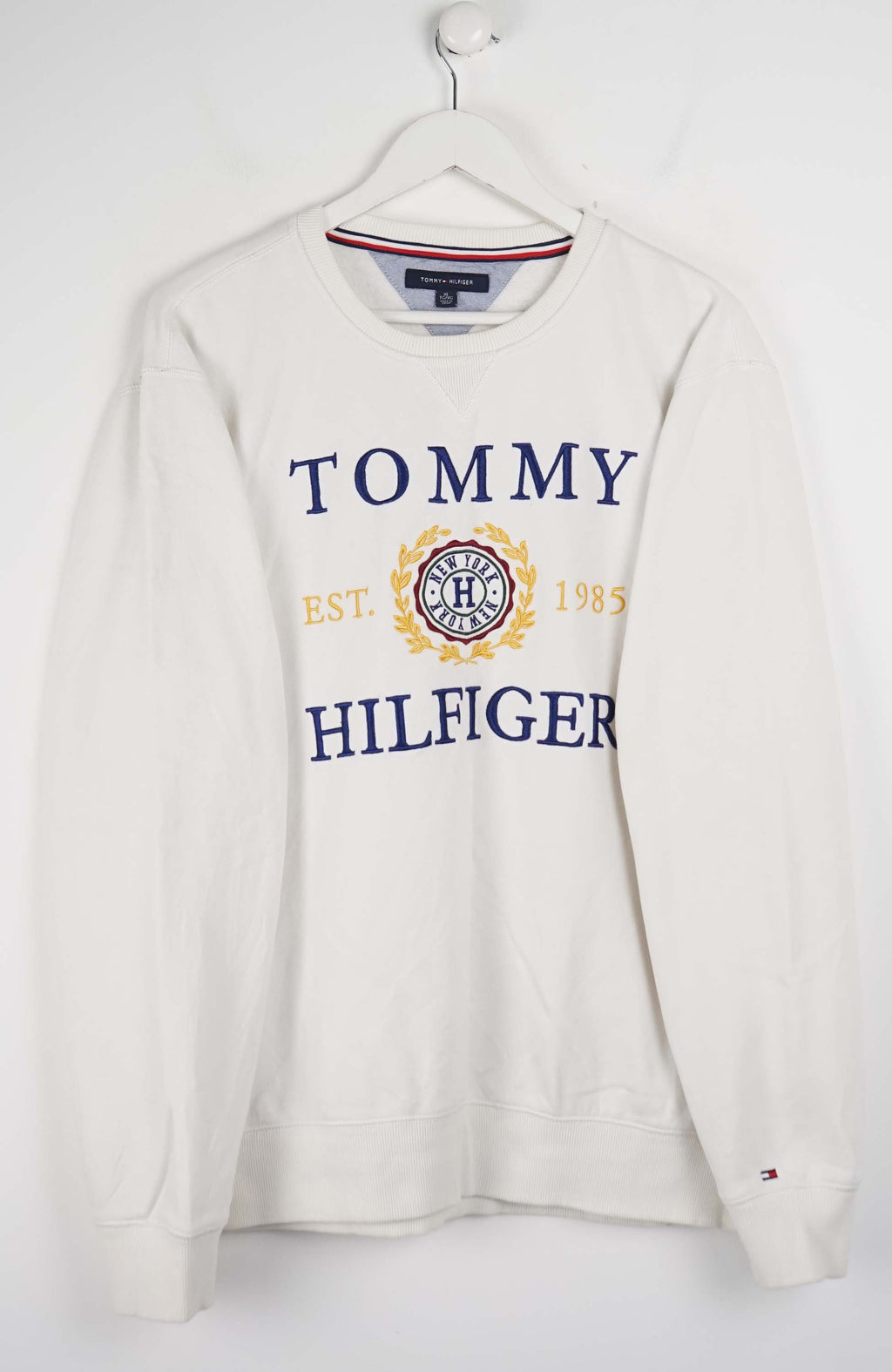 White Tommy Hilfiger sweatshirt on a hanger against a white background