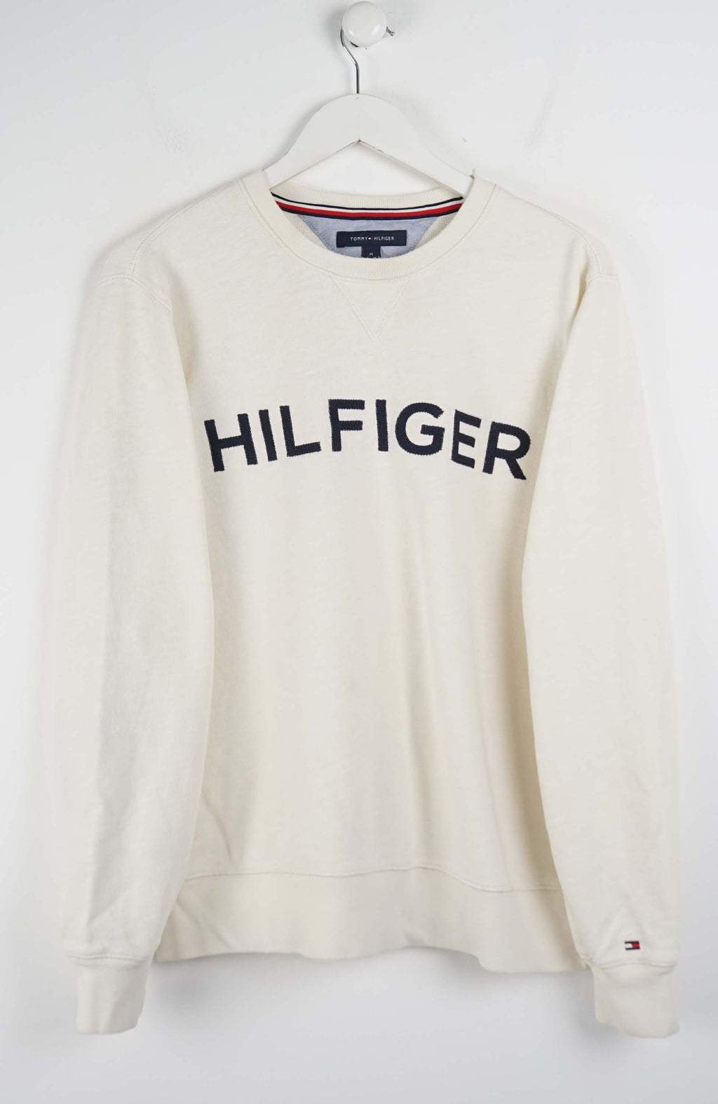 White Tommy Hilfiger sweatshirt on a hanger against a white background